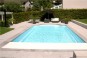 Une grande piscine rectangulaire avec escalier roman et fond en pente