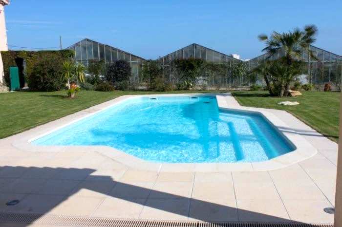 Piscine avec plage immergée et escalier coque polyester 9 x 5,20m fond incliné.