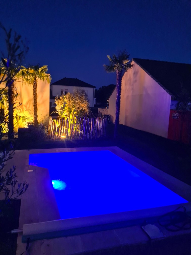 Petite piscine, rectangulaire, coque polyester. De nuit.